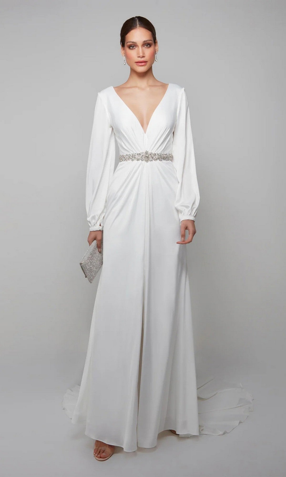 A woman in the Alyce 7070 long formal dress with a satin finish, deep V-neckline, and embellished waistband holds a silver clutch against a plain light background.